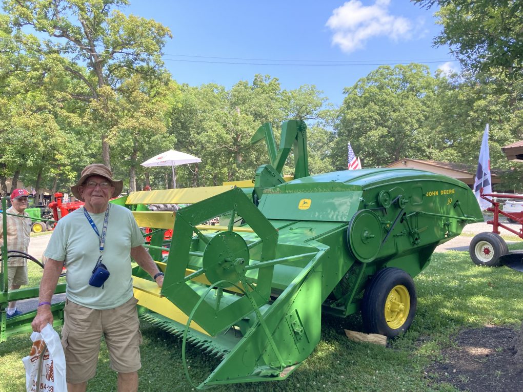 My dad in front of a old fashioned corn picker.